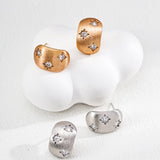 Pair of gold and silver earrings on a white background