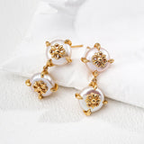 Pair of gold and pearl earrings on a white surface