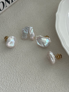 A set of baroque pearl earrings with 18K gold plating on brass, displayed on a white surface next to a plate.