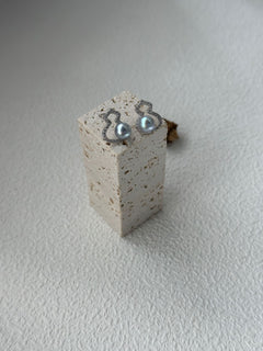Pair of earrings on a small concrete block against a light background