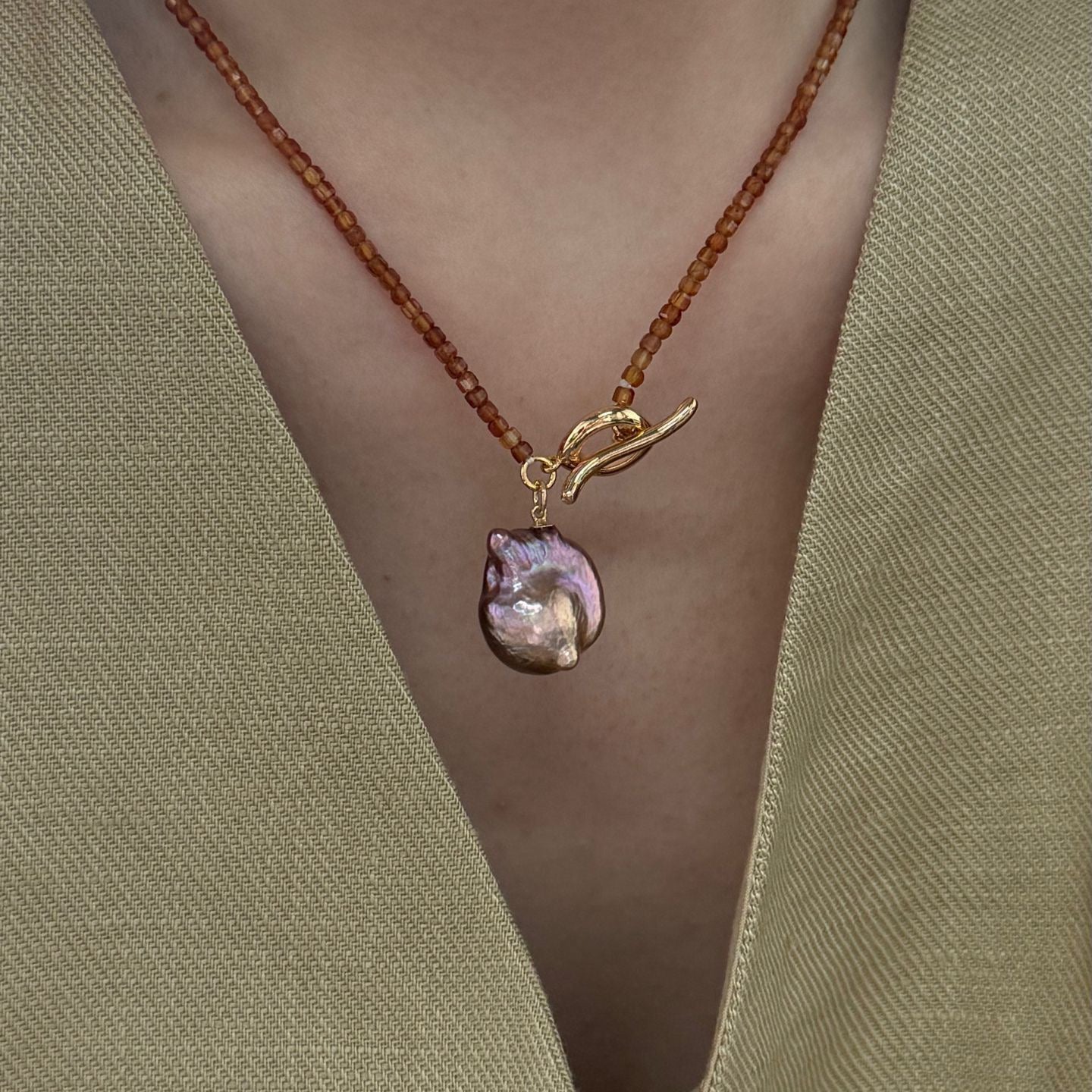 Necklace with a pendant on a green garment