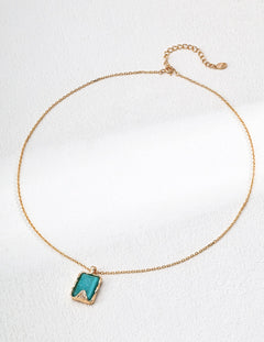 Gold necklace with a green pendant on a white background