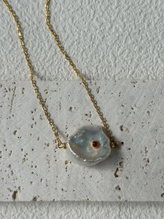 Necklace with a large, irregularly shaped pendant on a textured surface