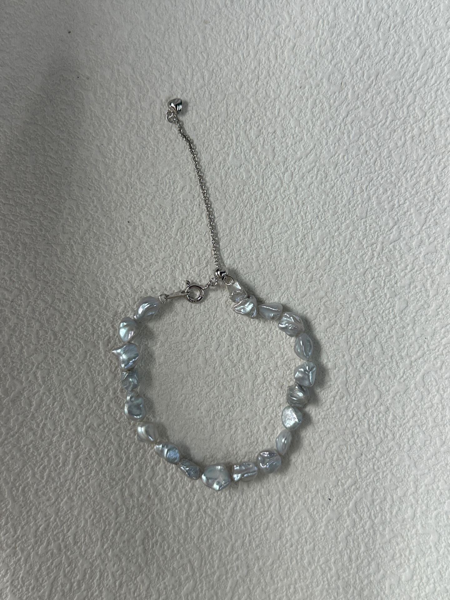 Silver beaded bracelet on a plain background