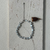 Bracelet with beads and a small decorative item on a textured surface