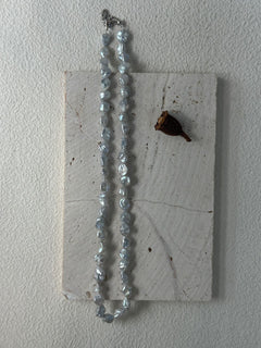 Necklace with blue beads on a textured white surface