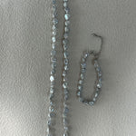 Necklace and bracelet set with clear stones on a light gray background