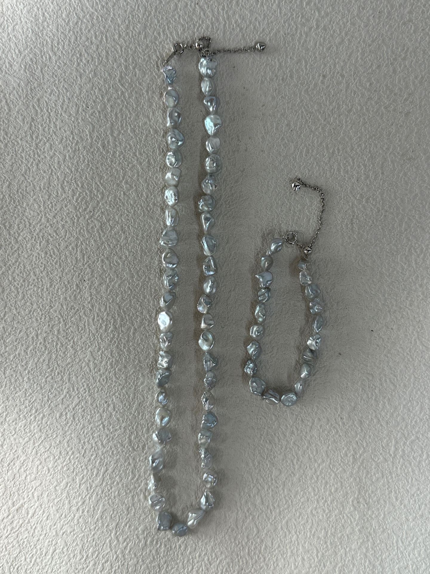 Necklace and bracelet set with clear stones on a light gray background
