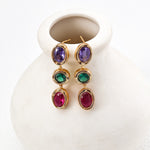 Colorful gemstone earrings on a white ceramic vase