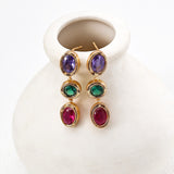 Colorful gemstone earrings on a white ceramic vase