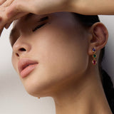 Close-up of a person wearing colorful earrings with a neutral background