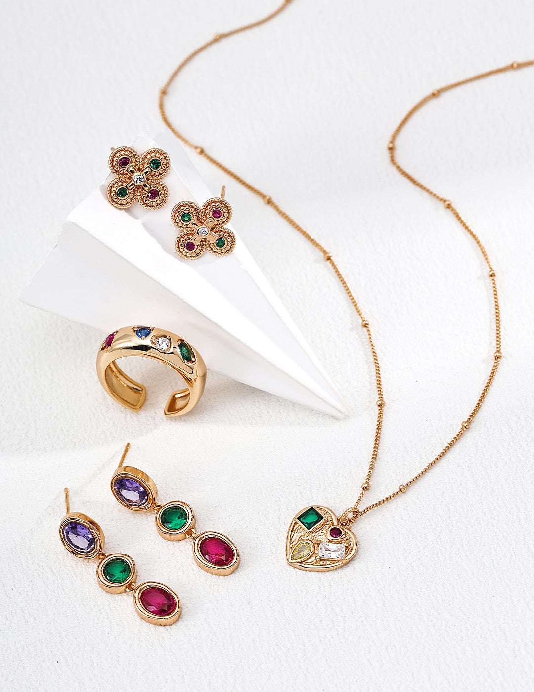 Gold jewelry set with colorful gemstones on a white background