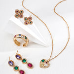 Gold jewelry set with colorful gemstones on a white background