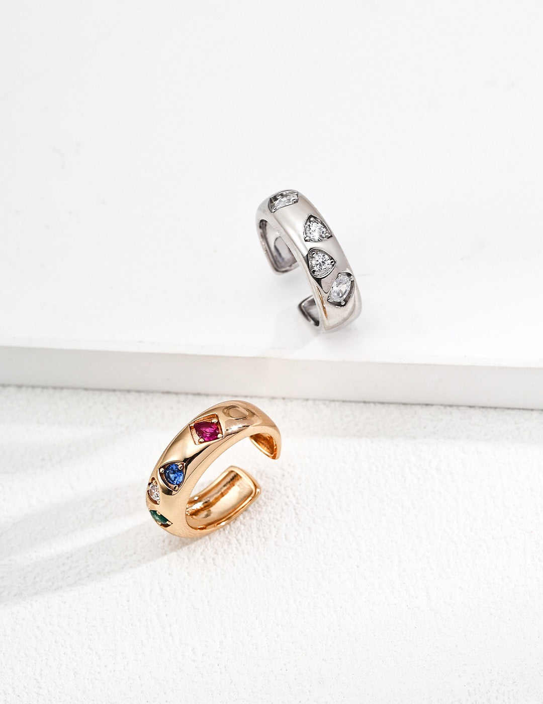 Two rings, one gold and one silver, on a white surface.