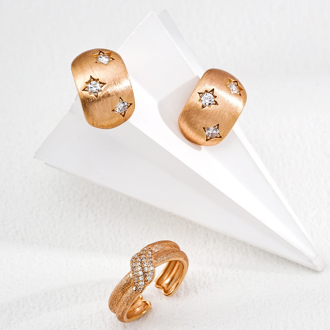 Pair of gold earrings with star designs on a white surface