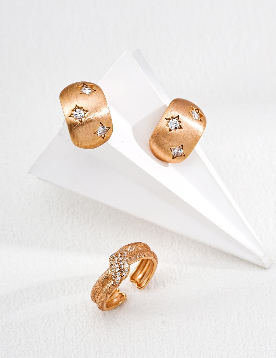 Pair of gold earrings with star designs on a white surface