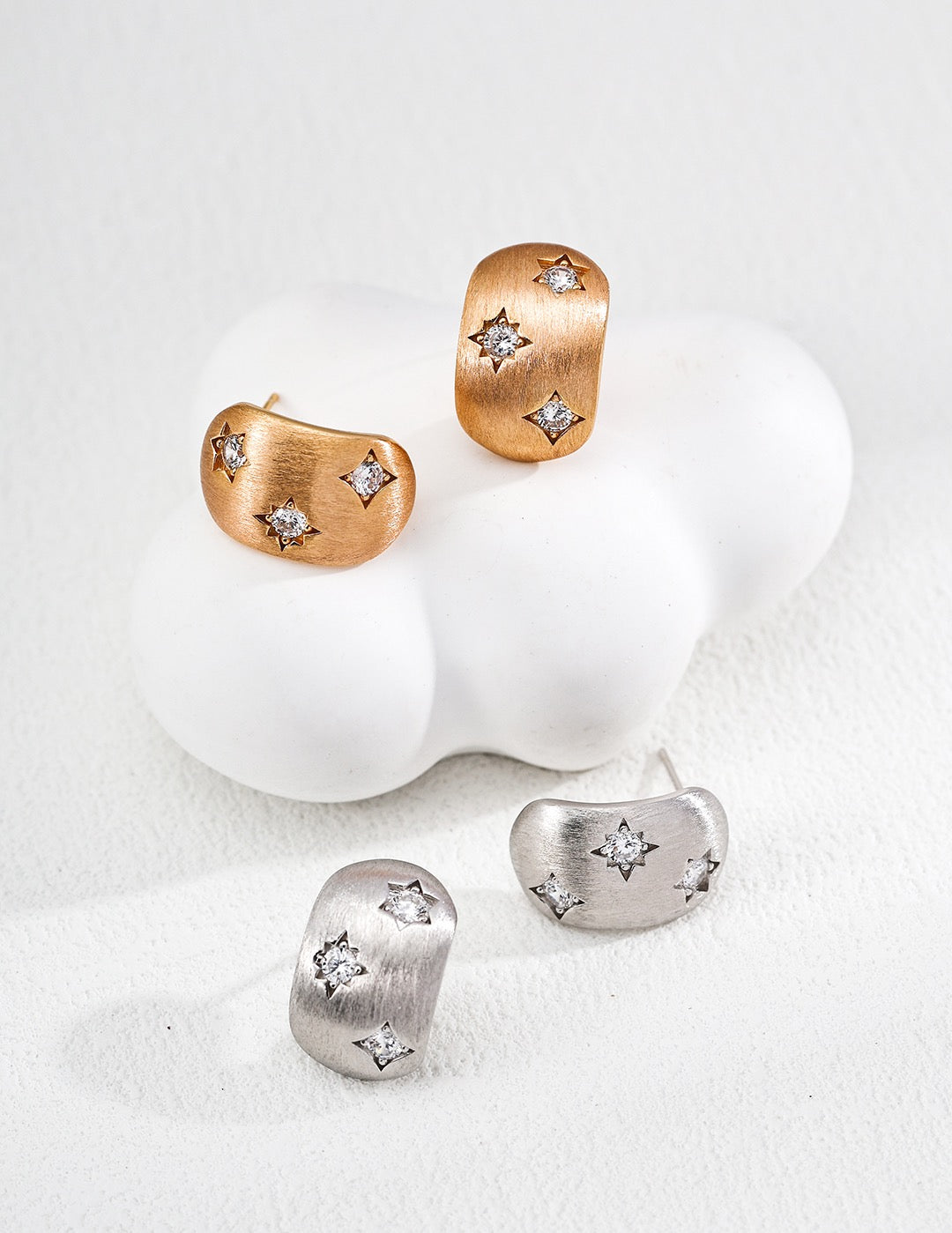 Pair of gold and silver earrings on a white background