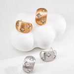 Pair of gold and silver earrings on a white background