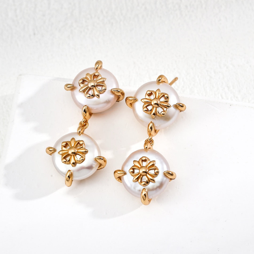 Pair of earrings with gold floral designs and pearl-like beads on a white background