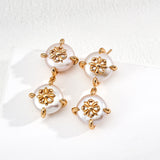 Pair of earrings with gold floral designs and pearl-like beads on a white background