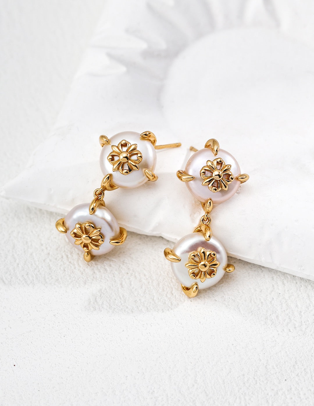 Pair of gold and pearl earrings on a white surface