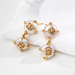 Pair of gold and pearl earrings on a white surface
