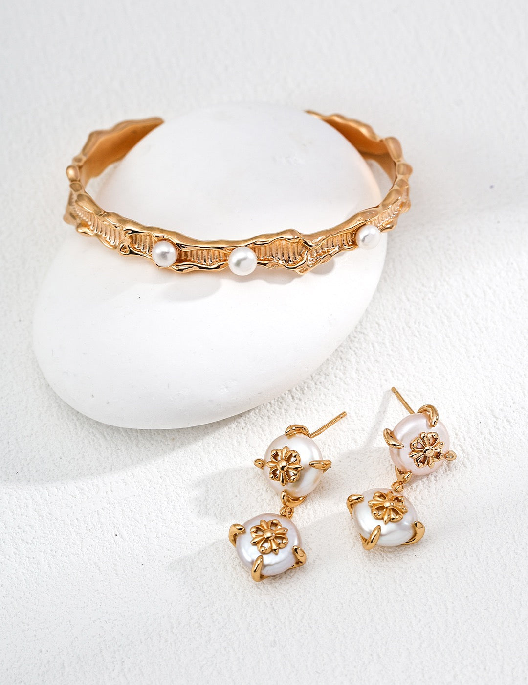 Gold and pearl jewelry set on a white background
