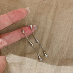 Silver hairpins held between fingers on a beige fabric background 