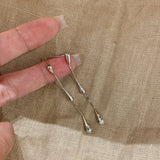 Silver hairpins held between fingers on a beige fabric background 