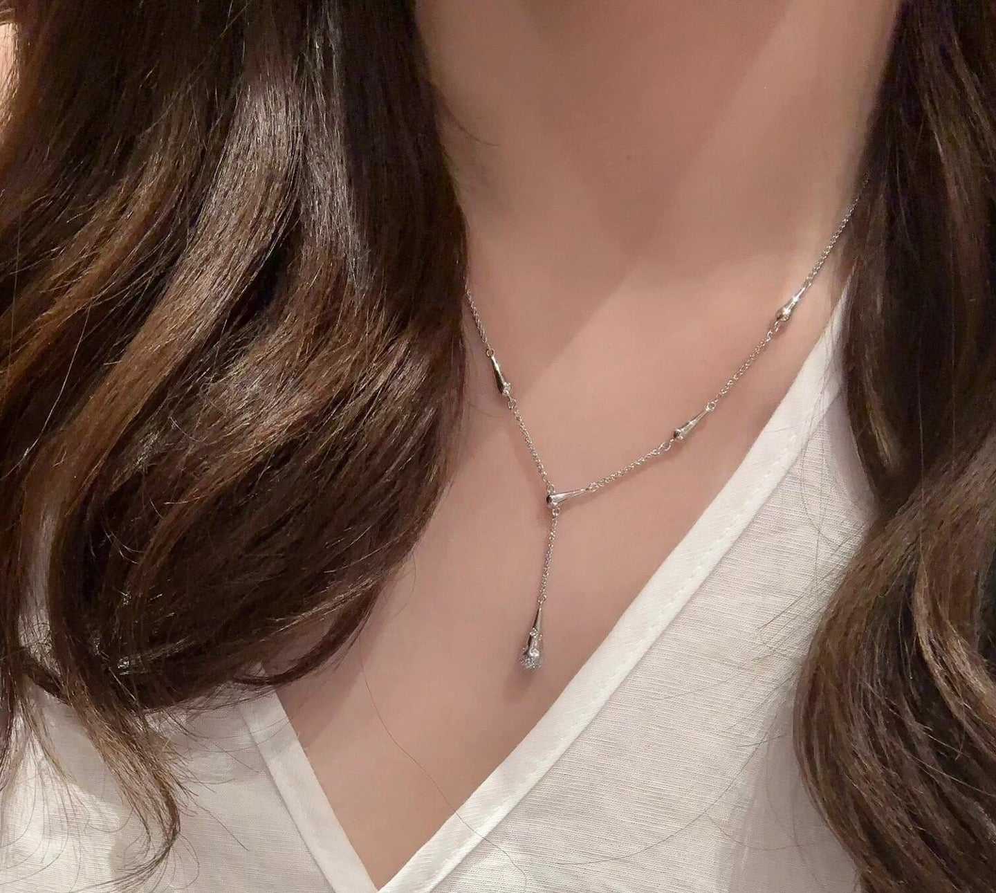 Necklace worn by a person with a visible brand logo on a neutral background