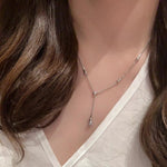 Necklace worn by a person with a visible brand logo on a neutral background