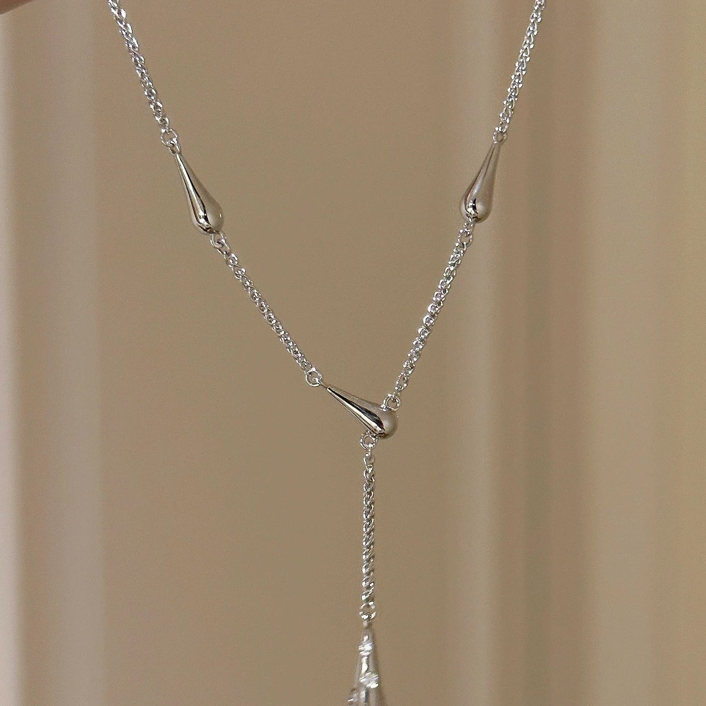 Silver necklace with a pendant on a beige background, featuring the brand 'CEISUR'.