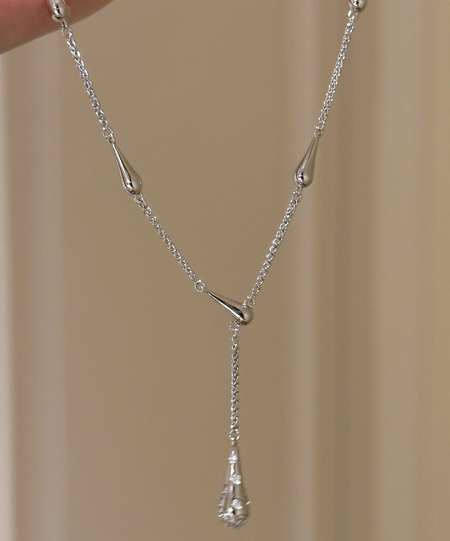 Silver necklace with a pendant on a beige background, featuring the brand 'CEISUR'.