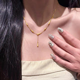 Gold necklace worn by a person with decorated nails