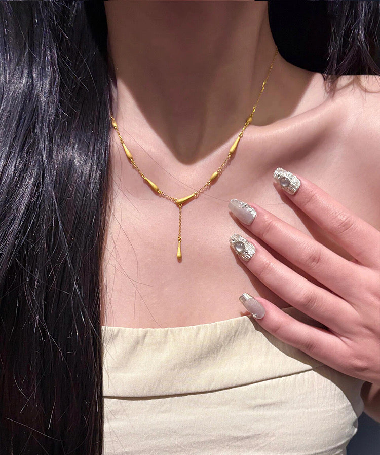 Gold necklace worn by a person with decorated nails